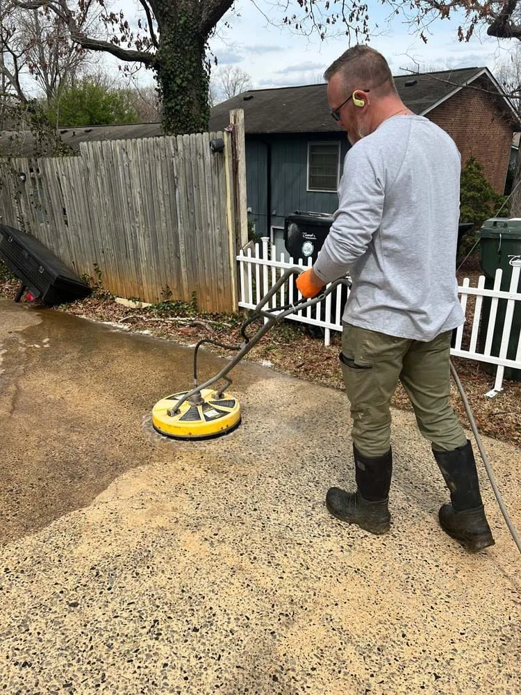 Pressure washing a walkway by a fence